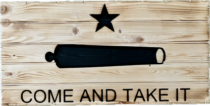 Wooden 'Come and Take It' flag featuring a rustic, weathered design. The flag displays the iconic cannon and star symbol with the phrase 'Come and Take It' engraved below, offering a bold, patriotic statement. Perfect for indoor or outdoor display.